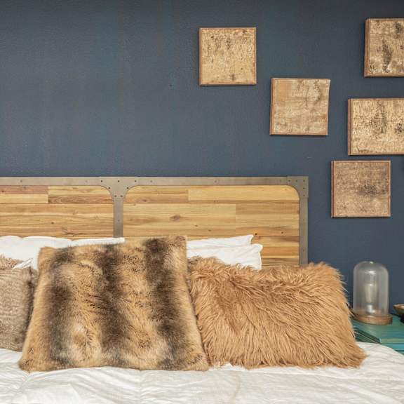 a bed with a wooden headboard and multiple pillows. at the cove at state street apartments, baton rouge, la, 70802