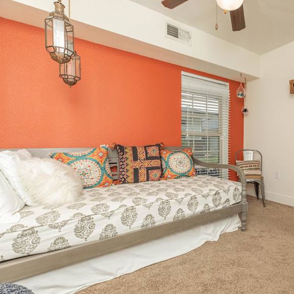 a bedroom with orange walls and a bed with a white comforter. at the cove at state street apartments, baton rouge