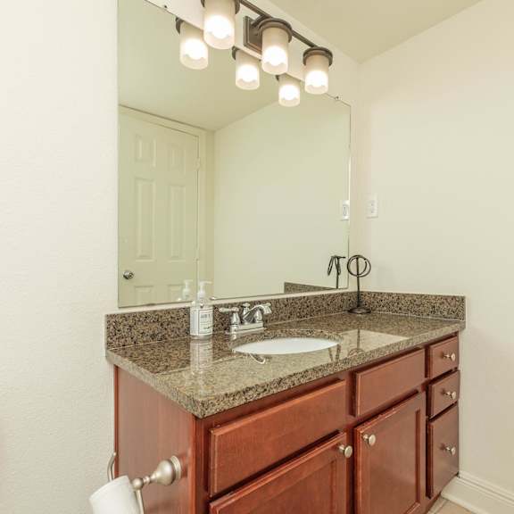a bathroom with a sink, mirror, and lights. at the cove at state street apartments, louisiana, 70802