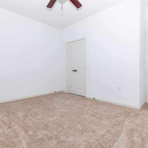 an empty room with a white door and carpet