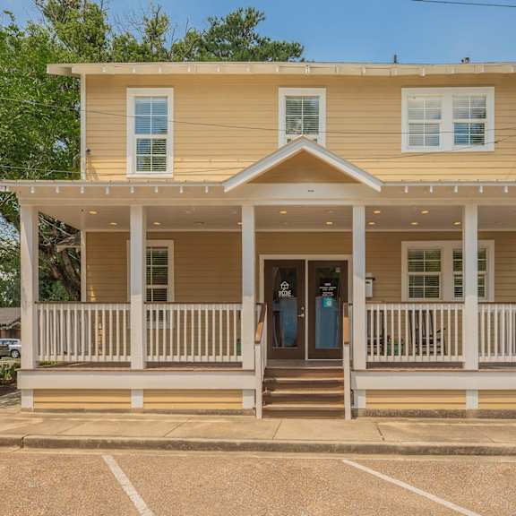 a yellow house with a porch and a white fence. at the cove at state street apartments, baton rouge, la, 70802