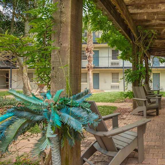 a patio with a table and chairs under a roof. at the cove at state street apartments, baton rouge