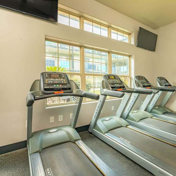 a treadmill room with a tv mounted on the wall. at the cove at state street apartments, baton rouge, la