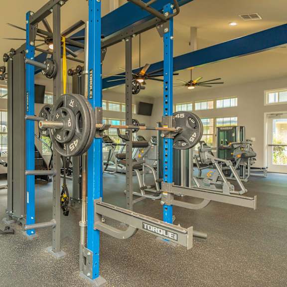 a gym with a weightlifting rack and other equipment. at the cove at state street apartments, louisiana