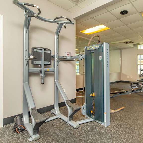 a gym with a weight machine and a row of treadmills. at the cove at state street apartments, baton rouge, la, 70802