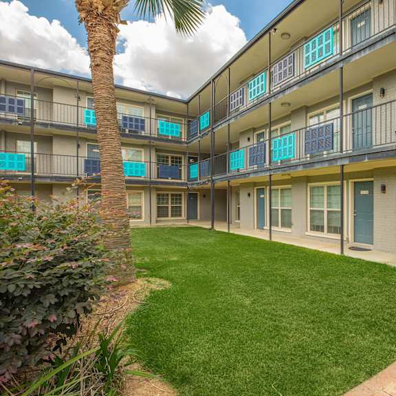 a sunny day at apartment complex with a palm tree in the front yard. at the cove at state street apartments, baton rouge, louisiana