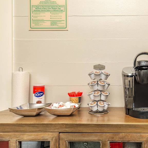 a coffee maker is on a wooden counter with a sign above it. at the cove at state street apartments, baton rouge, louisiana