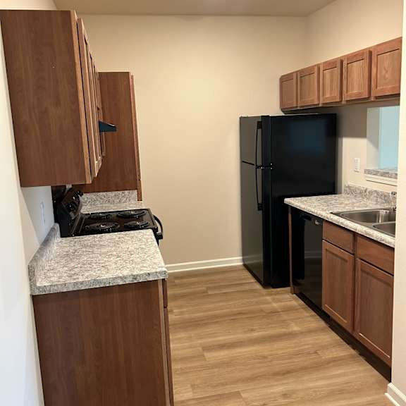 a kitchen with a black refrigerator and wooden cabinets.
