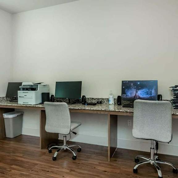 two desks with two computers and a printer in an office