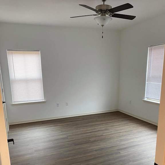 an empty room with wooden floors and a ceiling fan