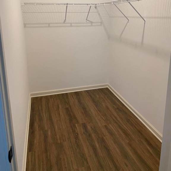 a room with white shelves on the wall and wooden floors