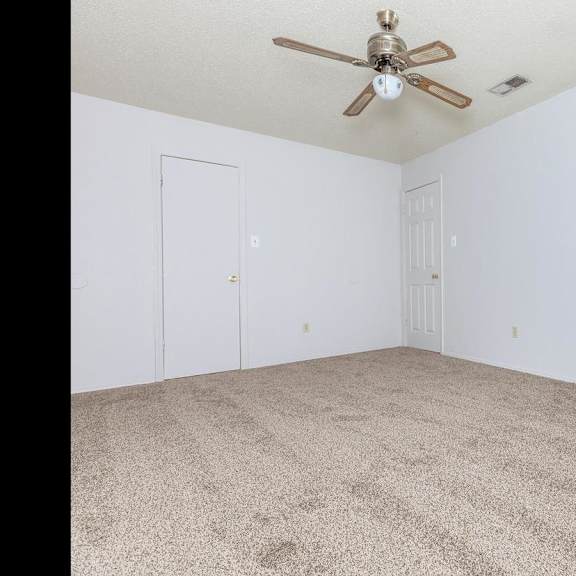a room with a ceiling fan and carpeted floor.