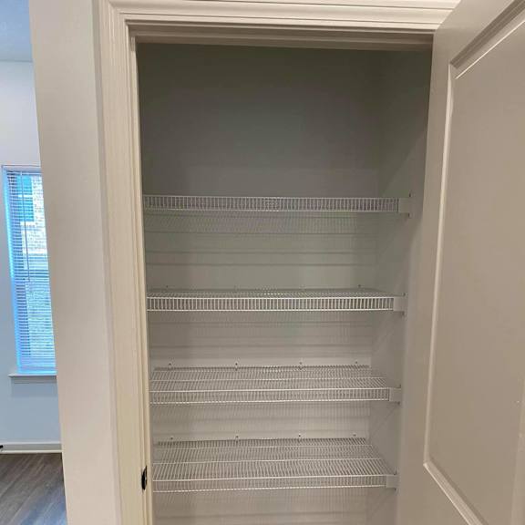 a walk in closet with white shelves and a door