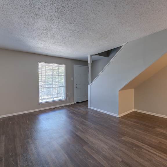 a room with wooden floors and a staircase leading to another room.