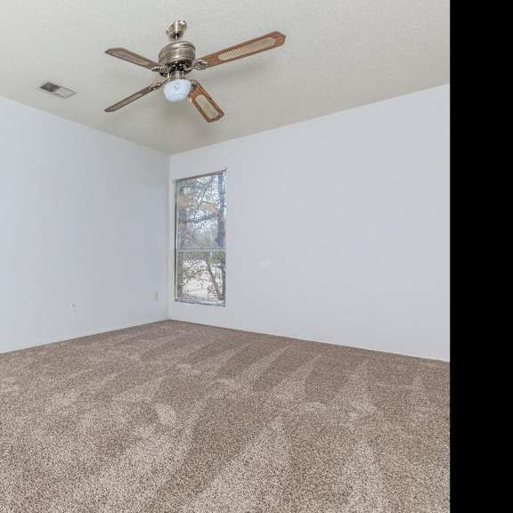 a room with a ceiling fan and carpeted floor.