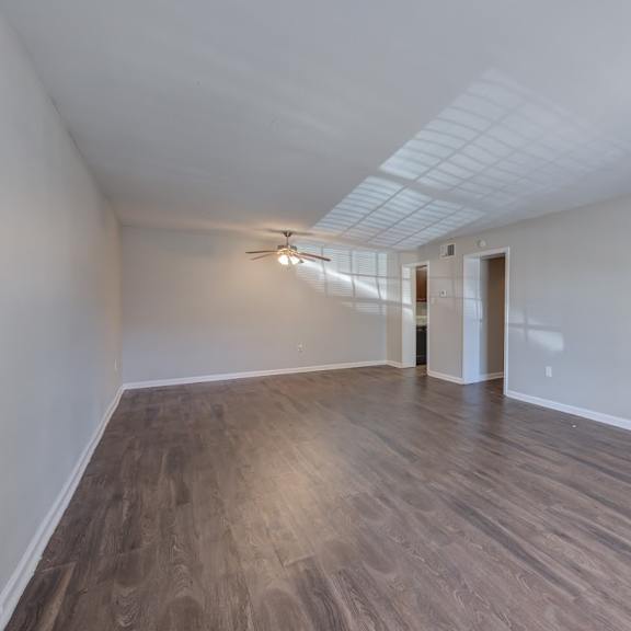 a room with a ceiling fan and light, and a door leading to another room.