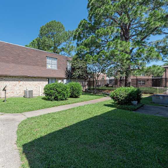 a building with a brown roof is surrounded by a green lawn and trees.