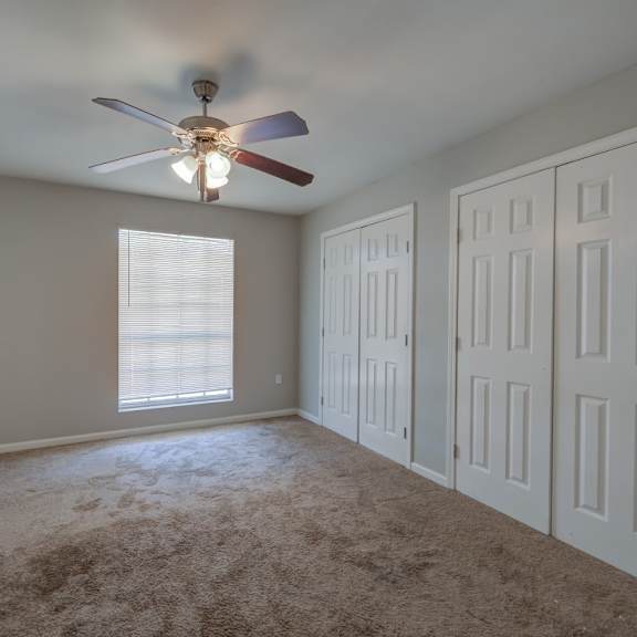 a room with a ceiling fan and carpeted floor.