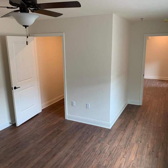 a bedroom with wood flooring and a closet and a ceiling fan