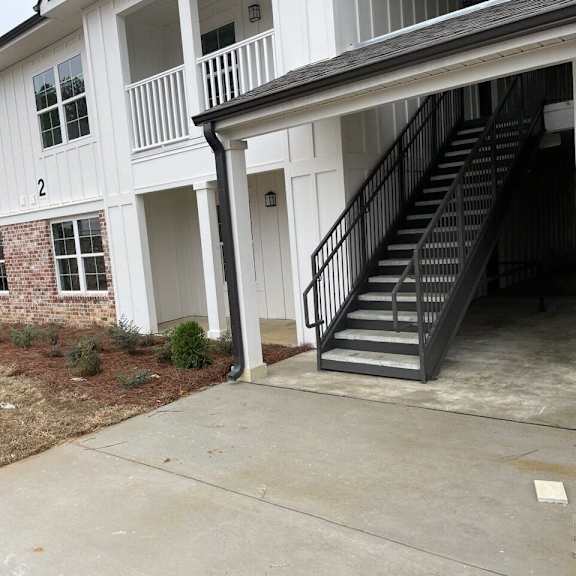 the front of a house with a concrete driveway and stairs