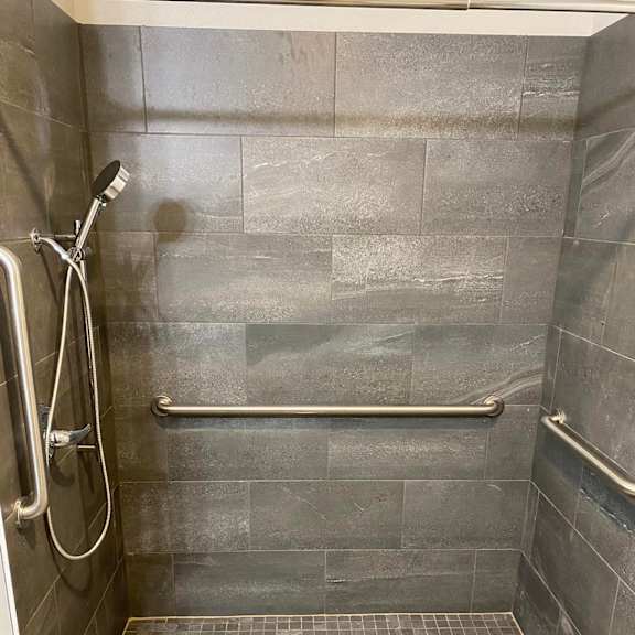 a shower with a tile floor and a tile wall.