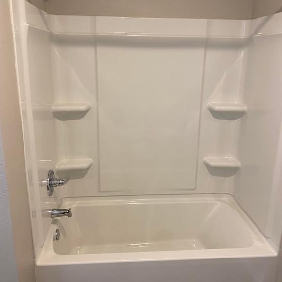 a white bathtub with a shower head above it.