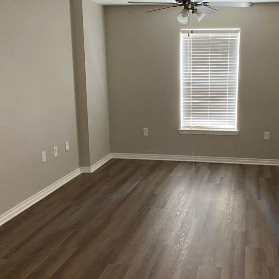 a room with a ceiling fan and a window with blinds.