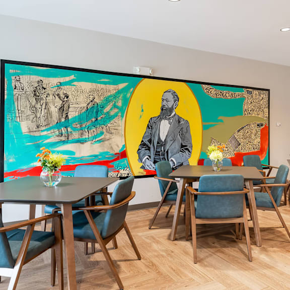 a dining room with a large painting on the wall and blue chairs.