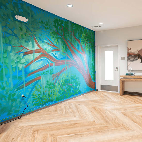 a room with a wooden floor and a mural of a tree on the wall.