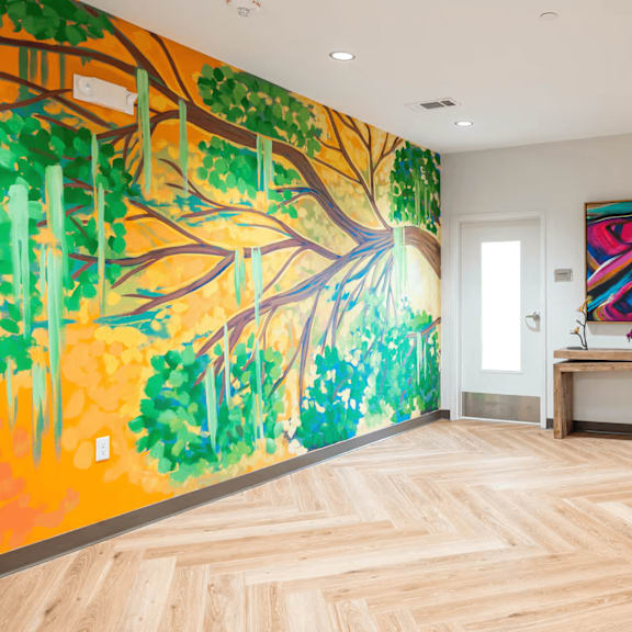 a room with a large painting of a tree on the wall.