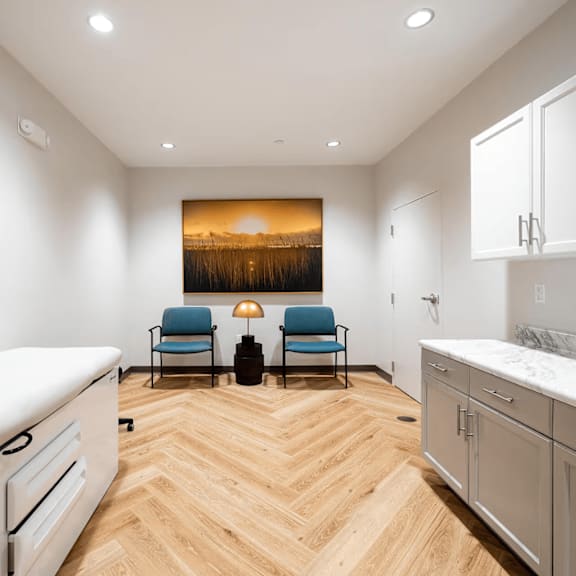 a modern kitchen with a wooden floor and a painting of a sunset on the wall.