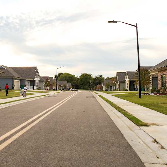 a street with houses on both sides and a person riding a bike down the street