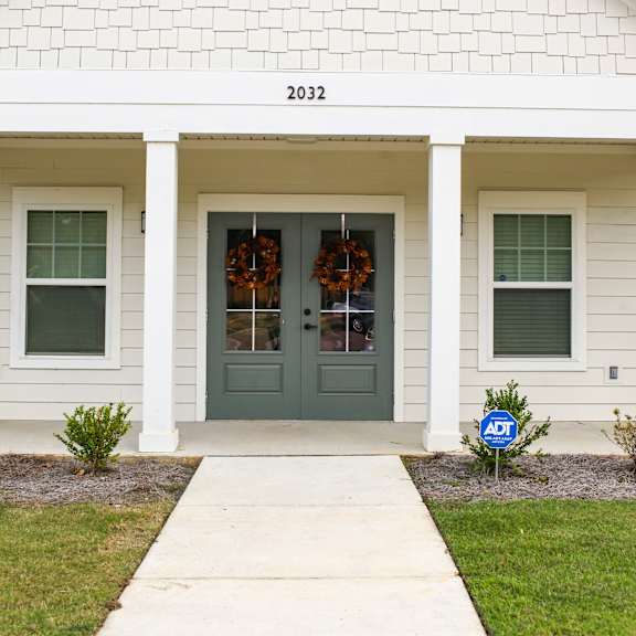 the front of a white house with a green door