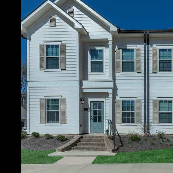 a white house with blue doors and a lawn