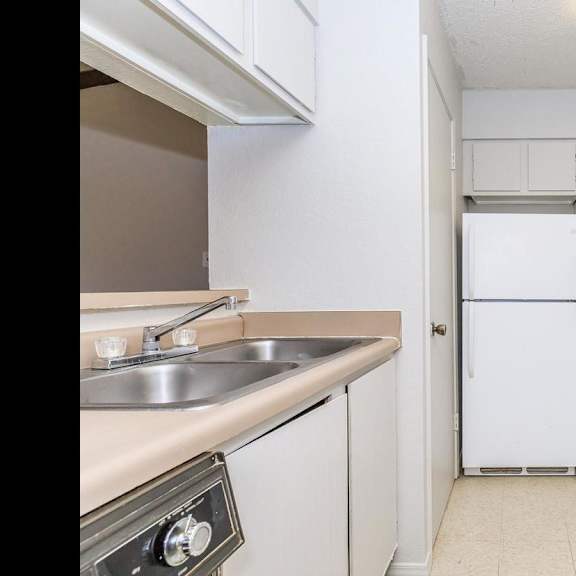 a white refrigerator is in the middle of a kitchen with white cabinets and a white stove.