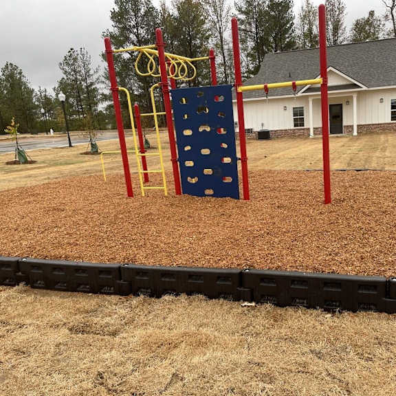 a playground with a blue rock wall in front of a house