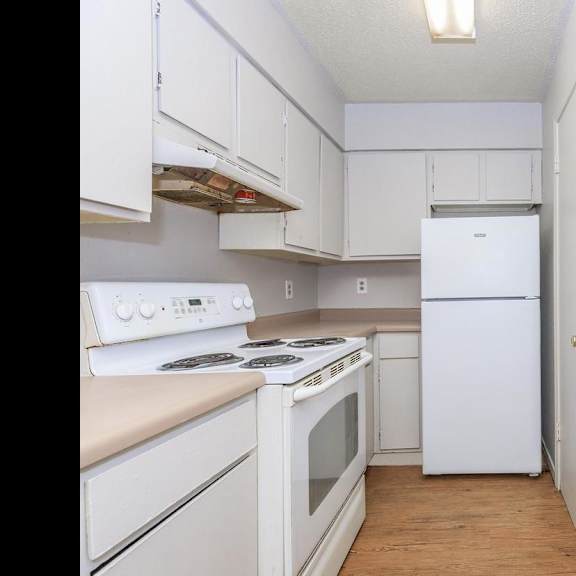 a white kitchen with a stove, refrigerator, and sink.