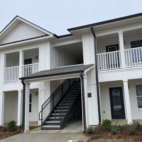 the front of an apartment building with stairs and a porch
