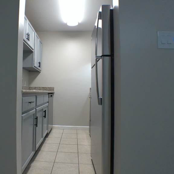 a kitchen with white cabinets and a stainless steel refrigerator