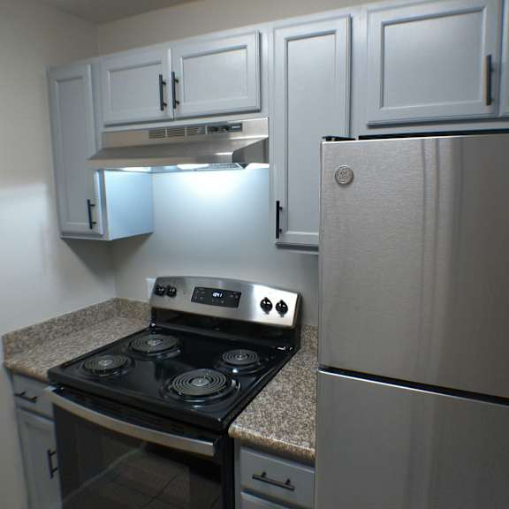 a kitchen with white cabinets and a stove and refrigerator