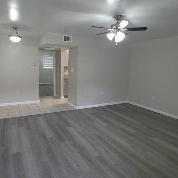 an empty living room with wooden floors and a ceiling fan