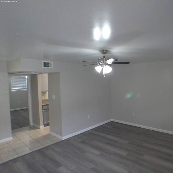 an empty living room with a ceiling fan