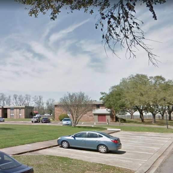a car is parked in a parking lot in front of a brick building.