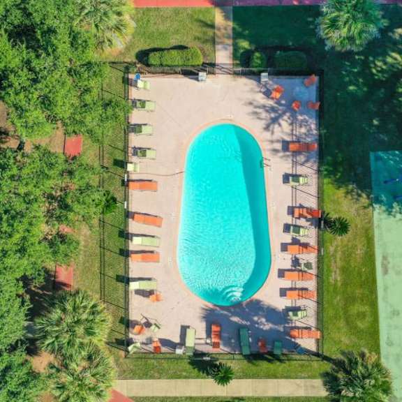 an aerial view of a swimming pool surrounded by trees and lounge chairs.