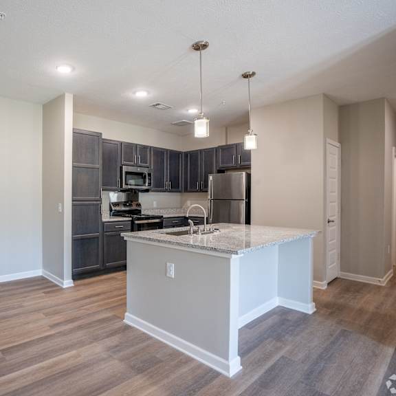a kitchen with a white island and wooden floors.