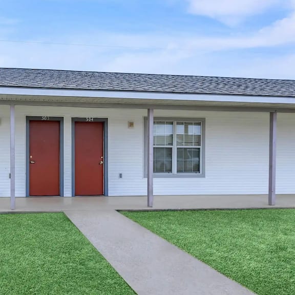 a white building with a red door and windows.