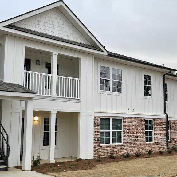 a white and brick house with a porch and a balcony