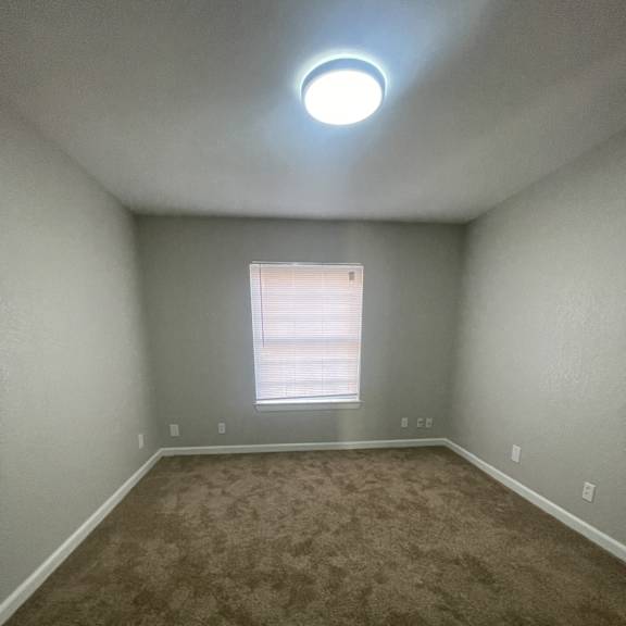 a room with a carpeted floor and a window with blinds.