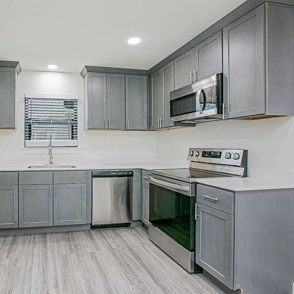 a kitchen with grey cabinets and stainless steel appliances.