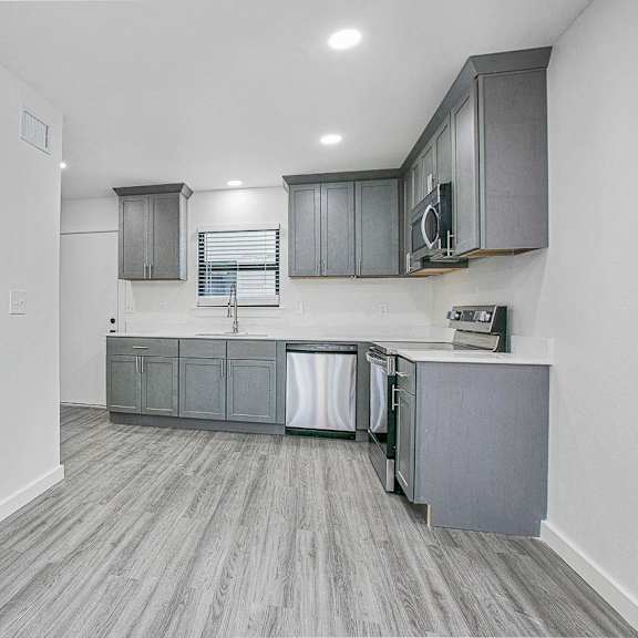 a kitchen with grey cabinets and a white door.